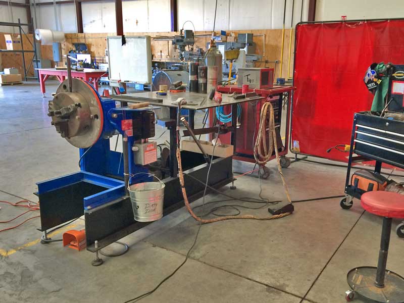 A machine is sitting in a warehouse next to a stool.