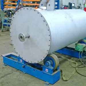 A large stainless steel tank is sitting on top of a blue base in a factory.