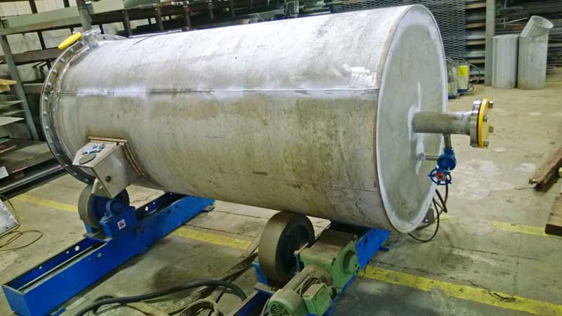 A large metal pipe is sitting on top of a machine in a factory.