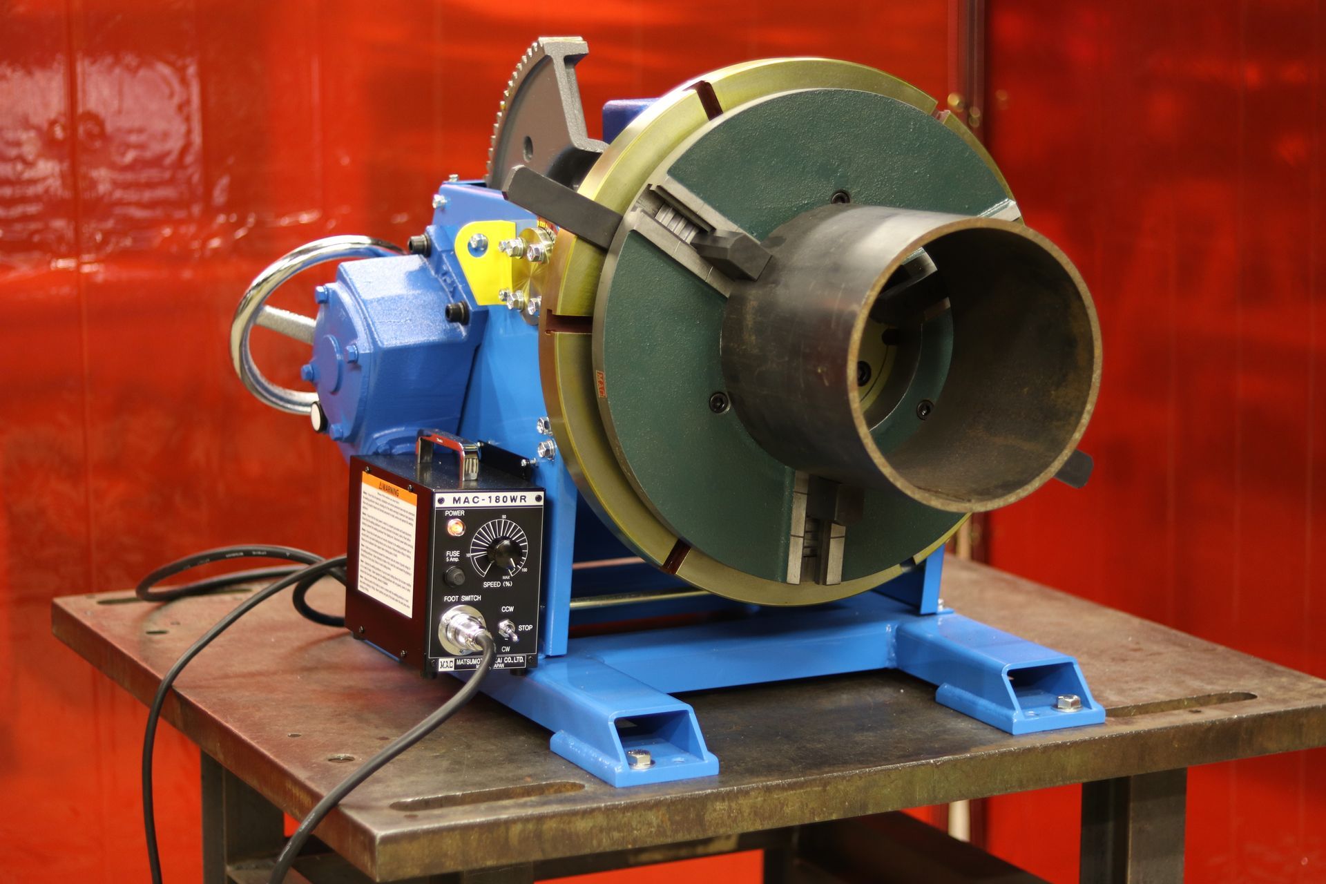 A machine is sitting on a table in front of a red curtain.