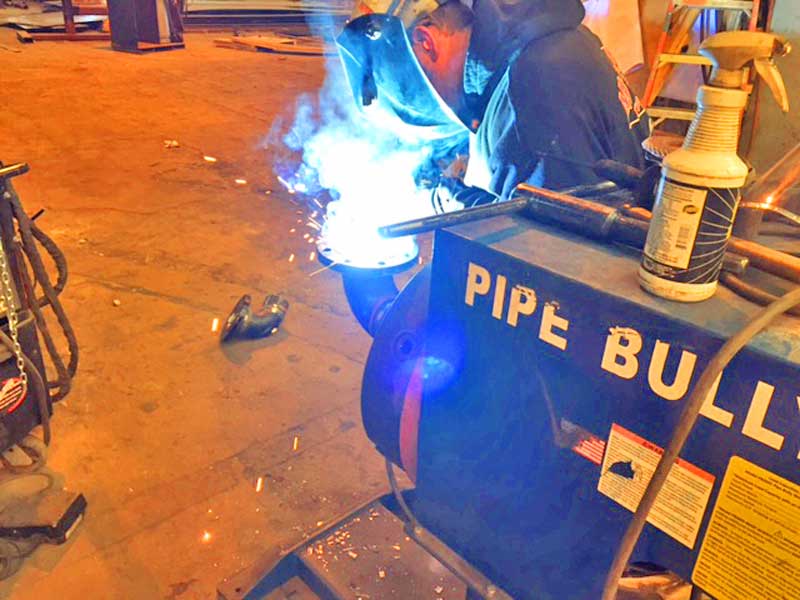 A man is welding a pipe on a pipe bull machine