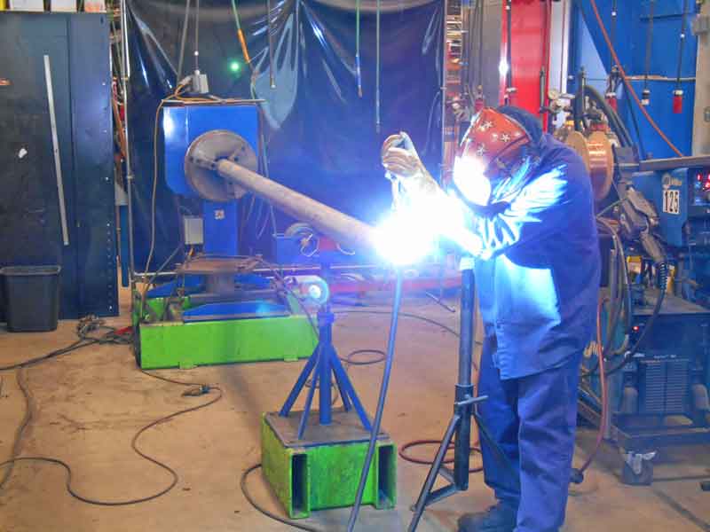 A man is welding a pipe in a factory