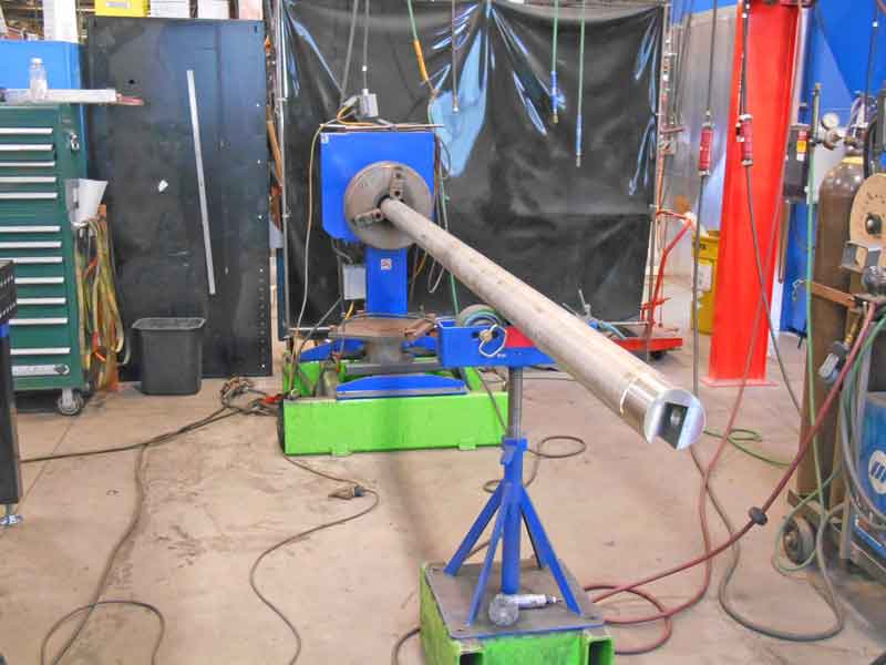A welding machine is sitting on a green stand in a workshop