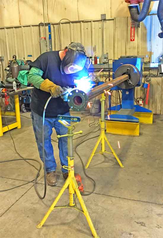 A man is welding a pipe in a factory