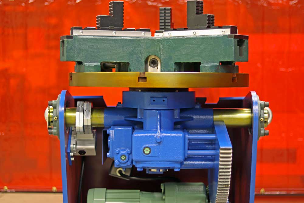 A blue and green machine is sitting on a table in front of a red curtain.