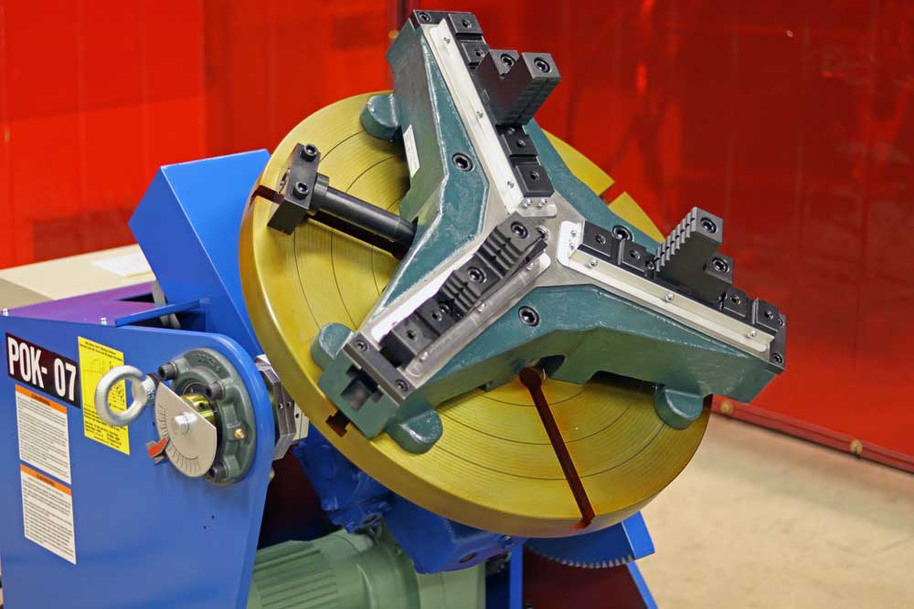 A machine is sitting in front of a red curtain in a factory.