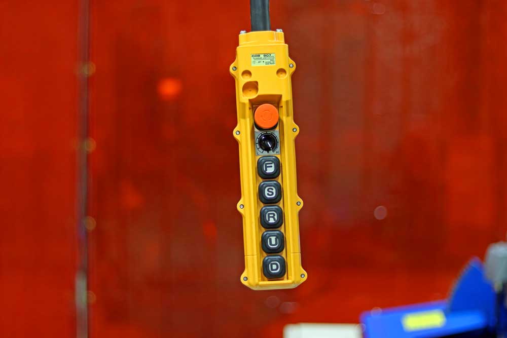 A yellow remote control is hanging from a crane.