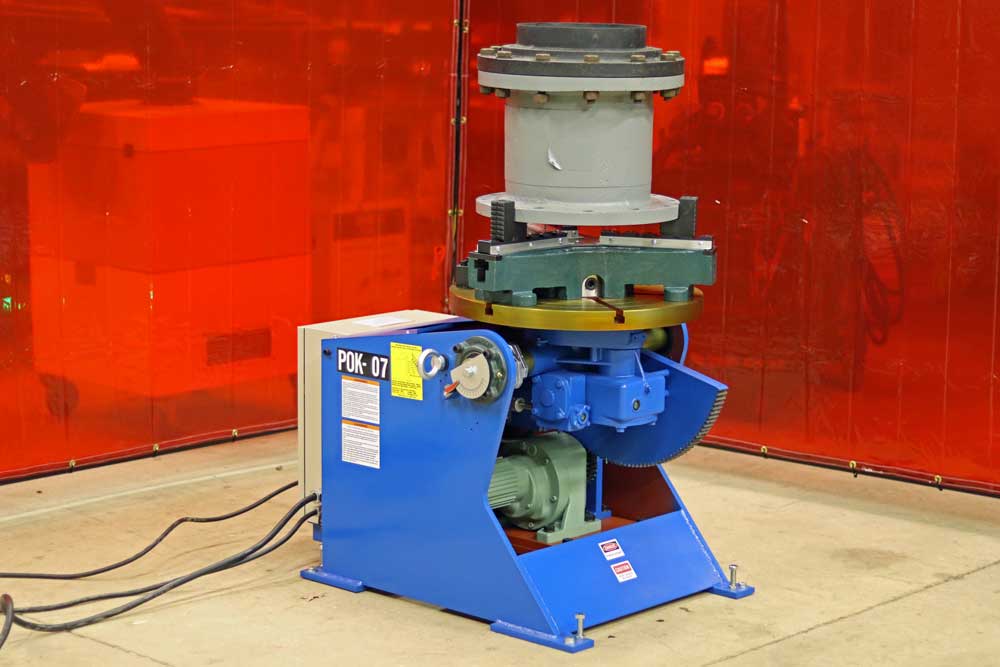 A blue machine is sitting on the floor in front of a red curtain.