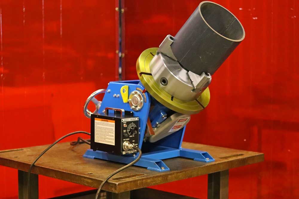 A machine is sitting on a wooden table in front of a red curtain.