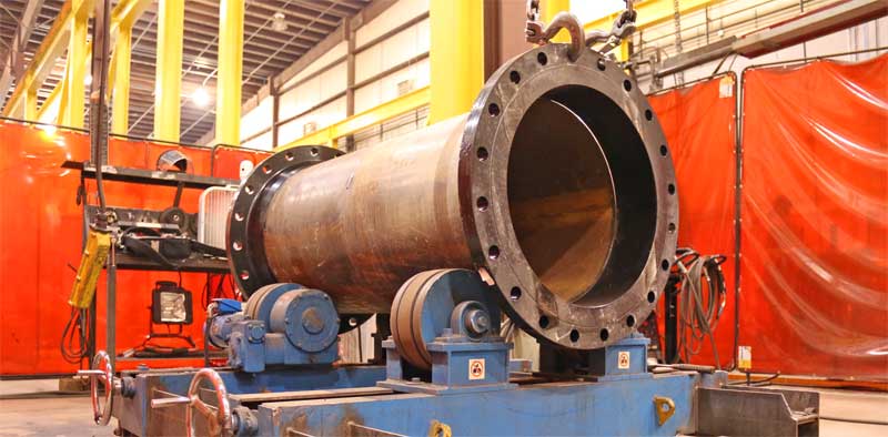 A large pipe is sitting on a machine in a factory.