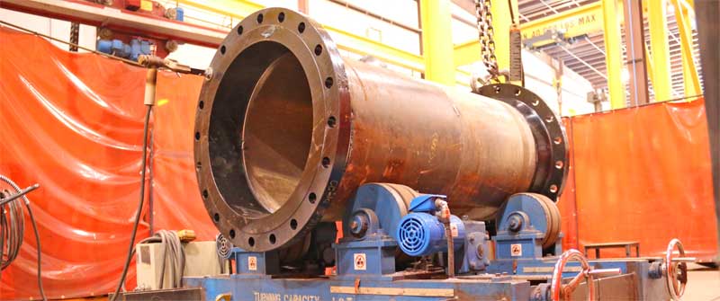 A large pipe is sitting on top of a machine in a factory.