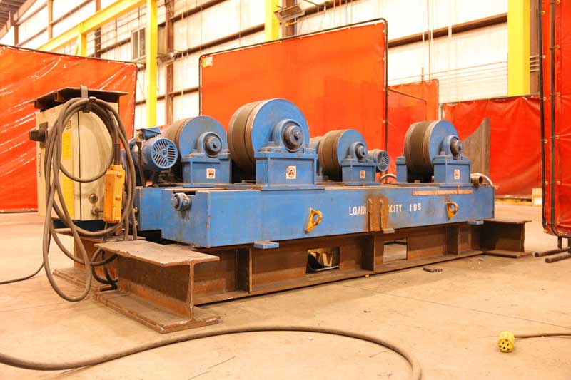 A blue machine is sitting in a warehouse next to a red curtain.