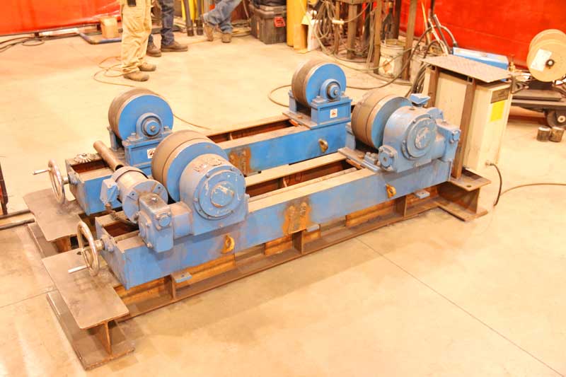 A blue machine is sitting on a concrete floor in a factory.