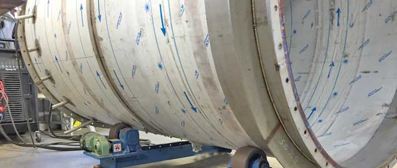 A large stainless steel tank is being built in a factory.