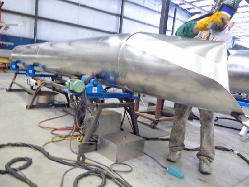 A man is welding a large piece of metal in a factory