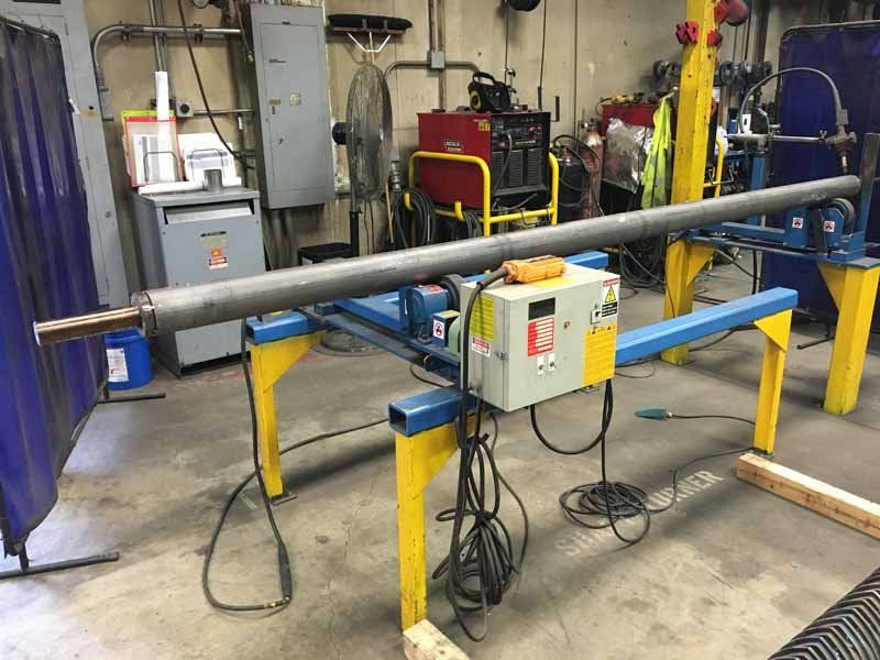 A large pipe is sitting on a machine in a workshop.