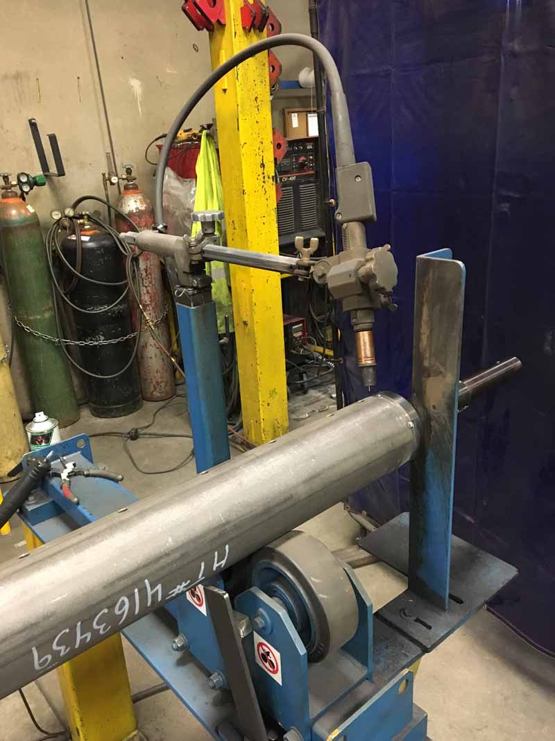 A machine is welding a pipe in a factory.