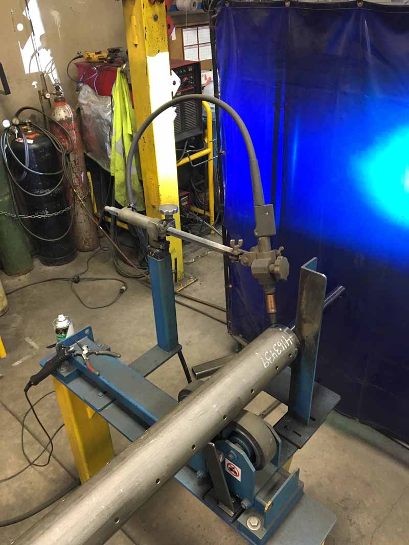 A machine is welding a pipe in a workshop.