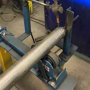 A large metal pipe is sitting on top of a machine.