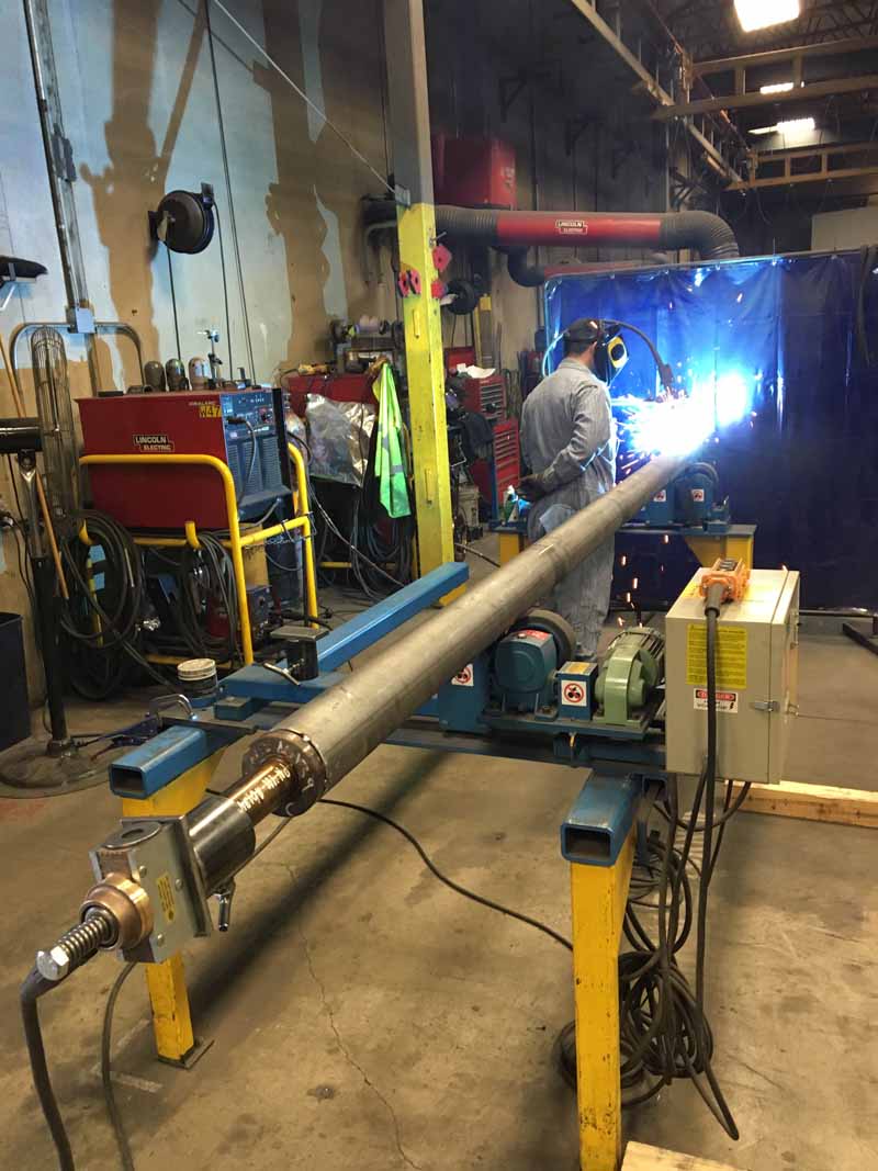 A man is welding a pipe in a factory.