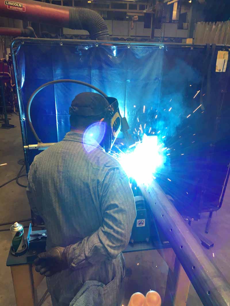 A man is welding a piece of metal in a factory.