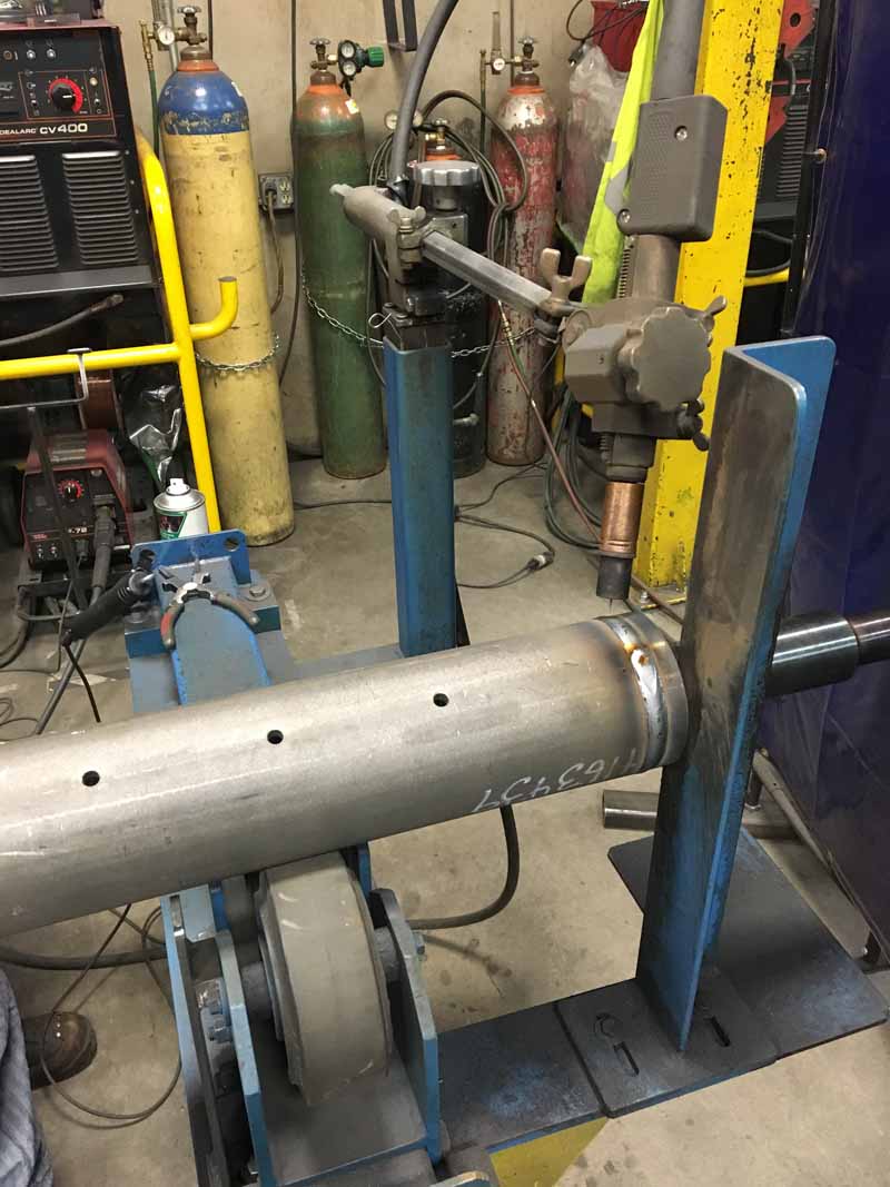 A machine is welding a pipe in a factory.
