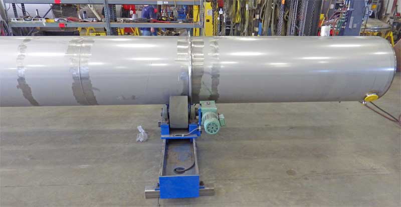 A large metal pipe is sitting on top of a concrete floor in a factory.