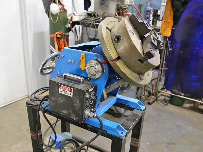 A welding machine is sitting on a table in a workshop.