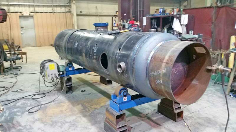 A large metal pipe is being welded in a factory.