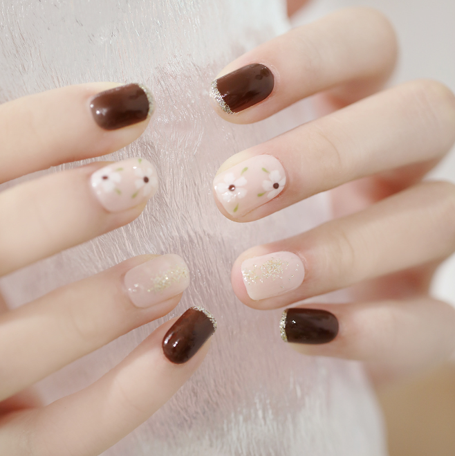 A close up of a woman 's nails with a brown and white design.