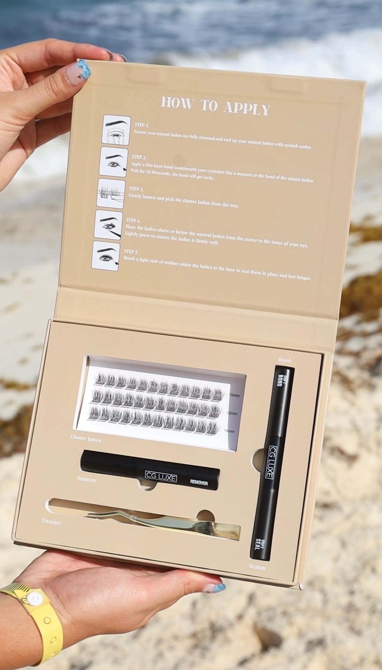 A woman is holding a cardboard box on the beach.