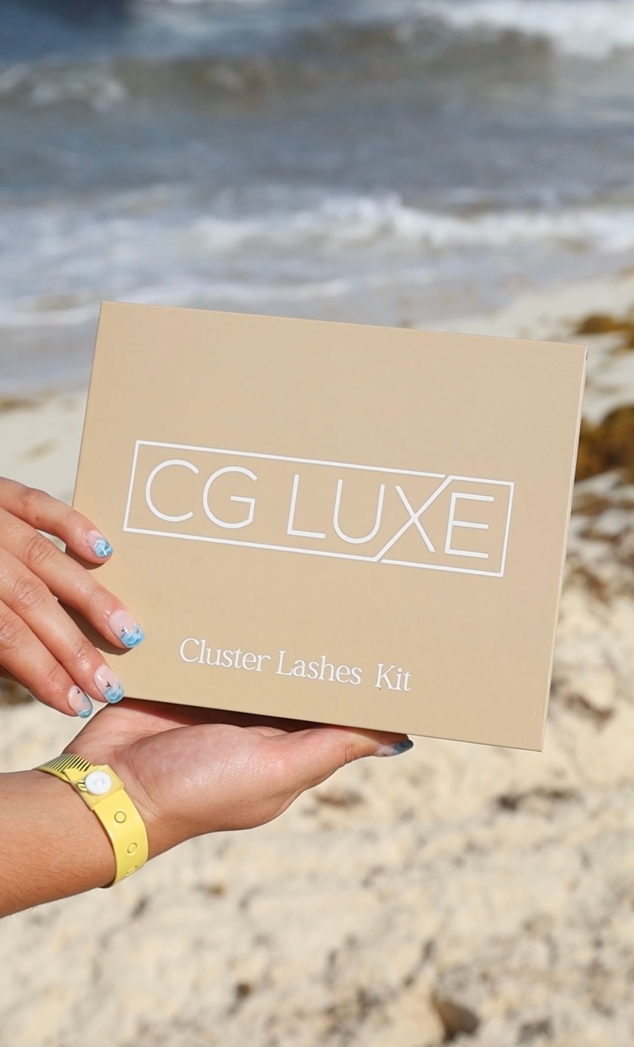 A woman is holding a cardboard box on the beach.