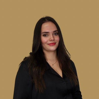 A woman wearing a black shirt and a necklace smiles for the camera