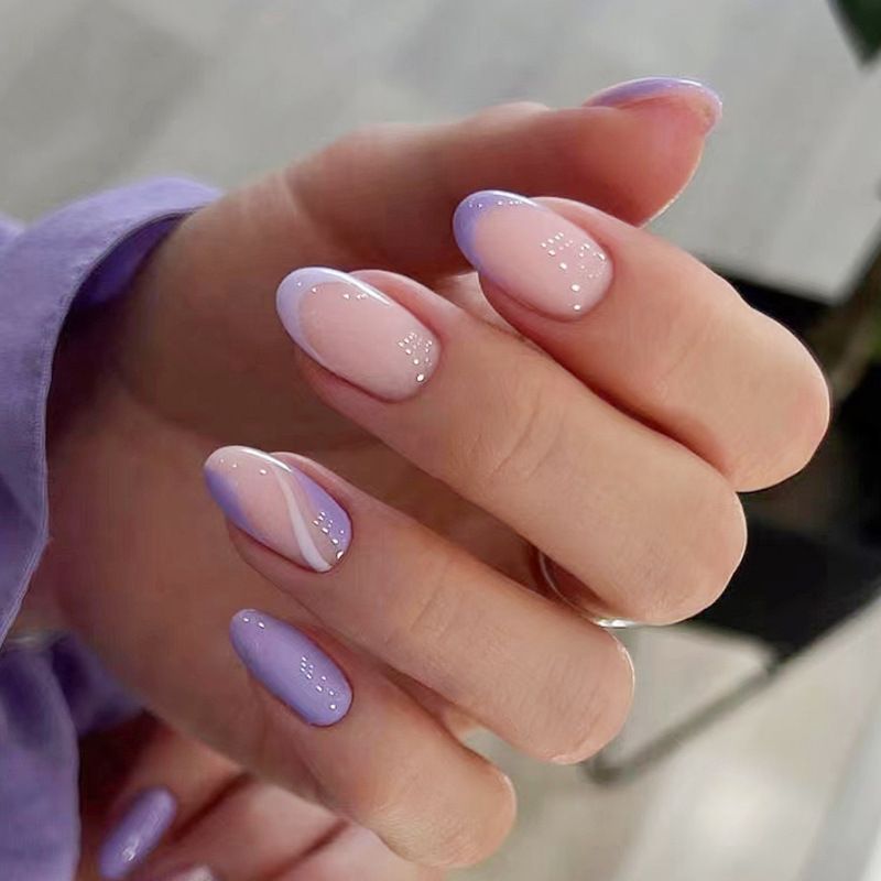 A close up of a woman 's hand with purple and pink nails.