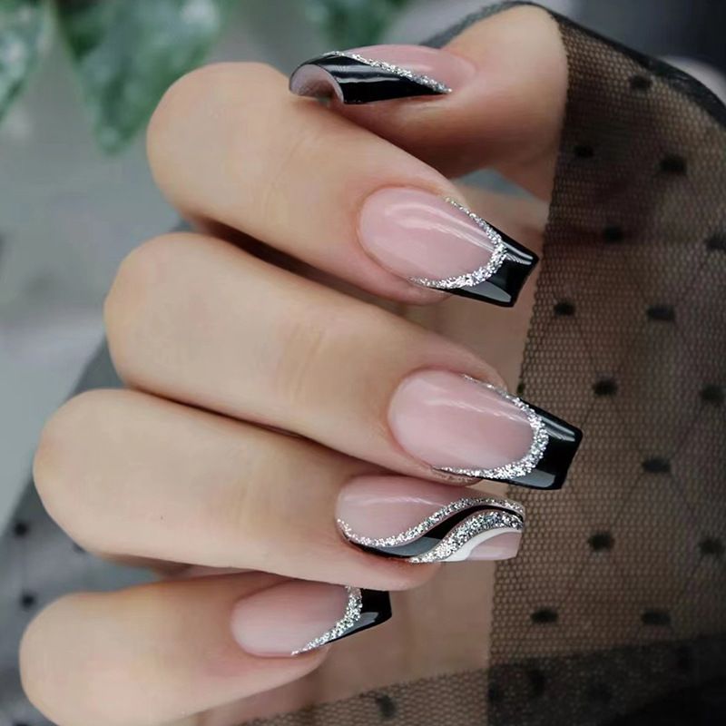A close up of a woman 's nails with a black and silver design