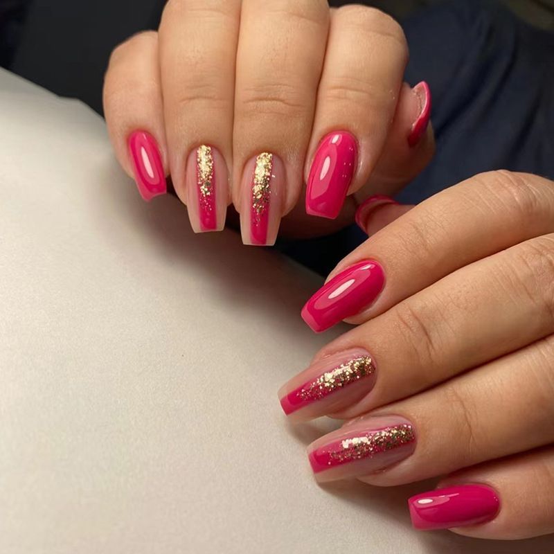 A close up of a woman 's pink nails with gold glitter