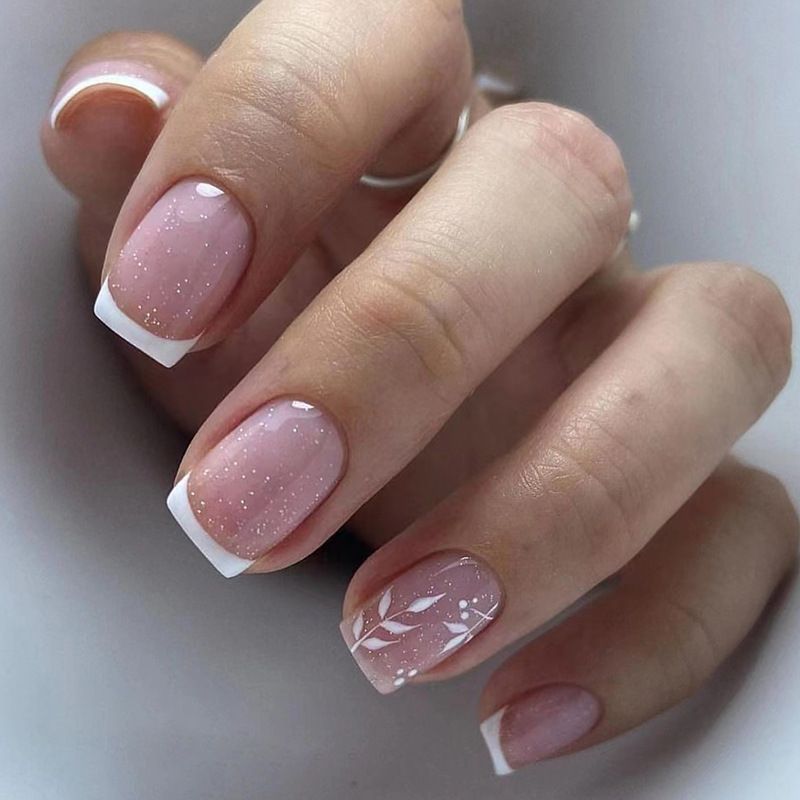 A close up of a woman 's nails with a white french manicure