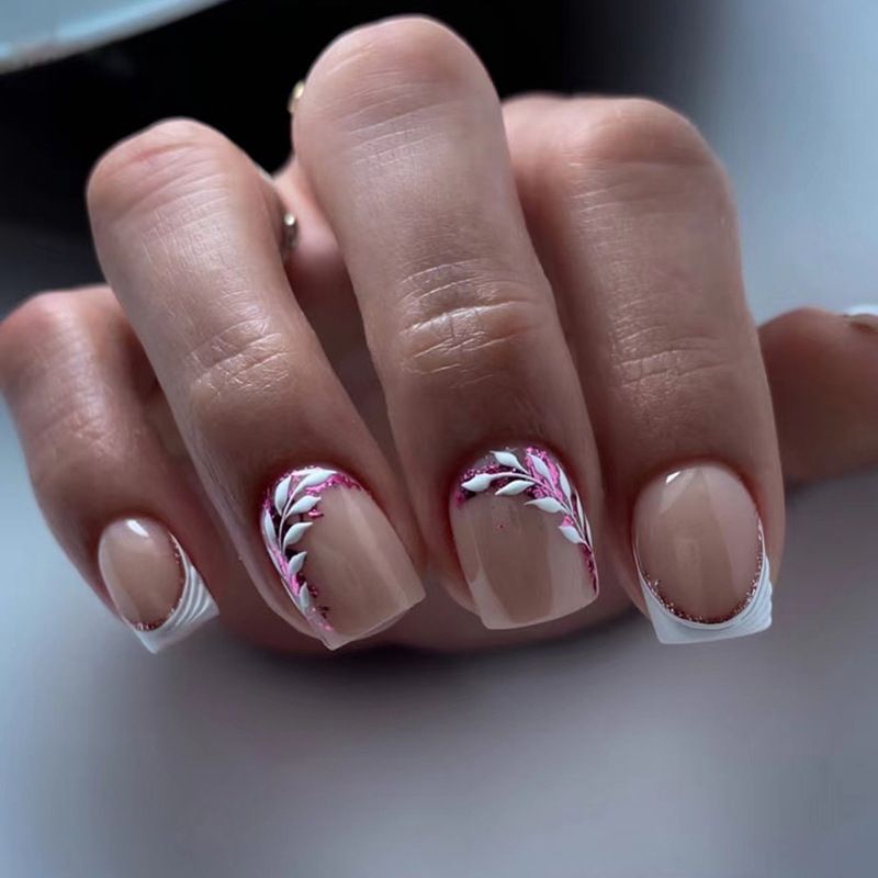 A close up of a woman 's nails with a floral design on them.