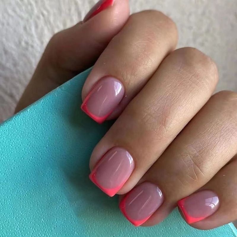 A close up of a person 's nails with a pink and red french manicure.