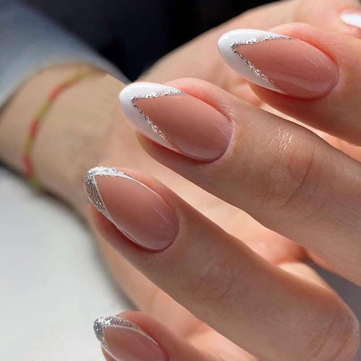 A close up of a woman 's nails with a white french manicure