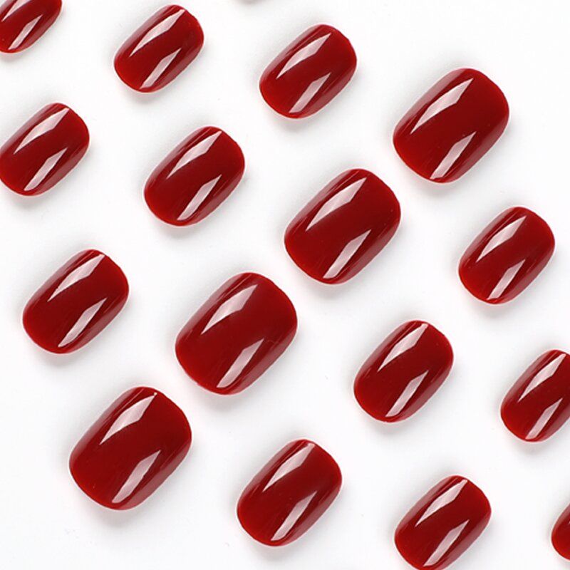 A woman wearing a white sweater has red nails