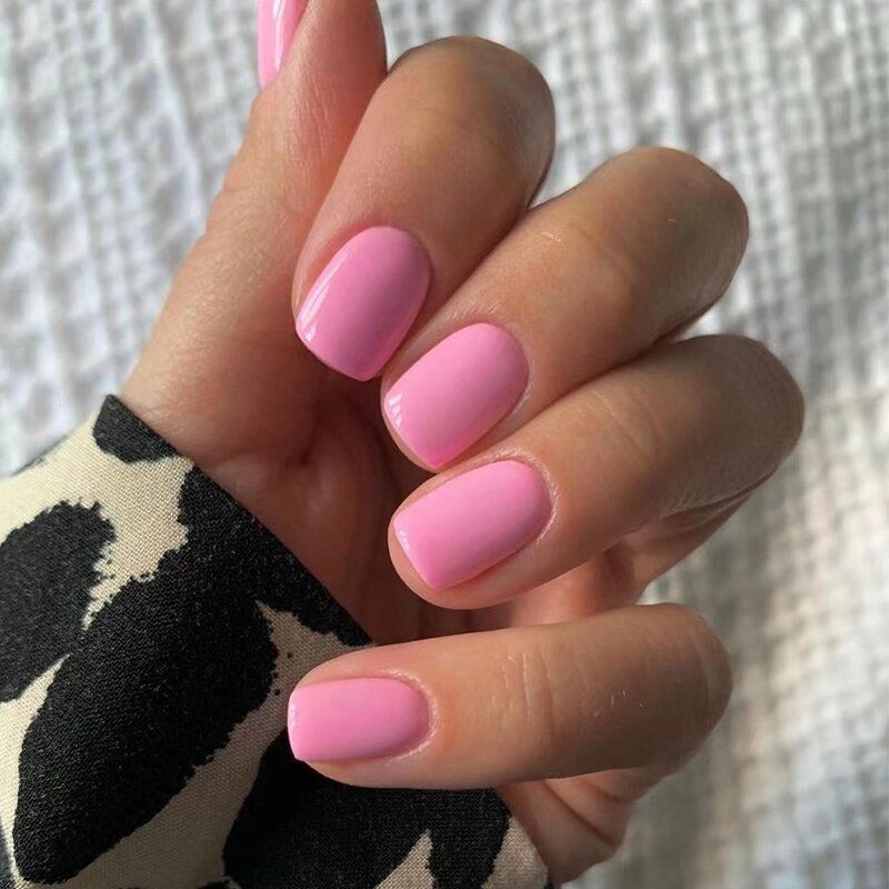 A close up of a woman 's hand with pink nails.