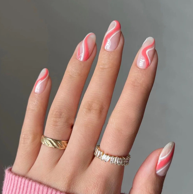 A close up of a woman 's nails with a pink and white design