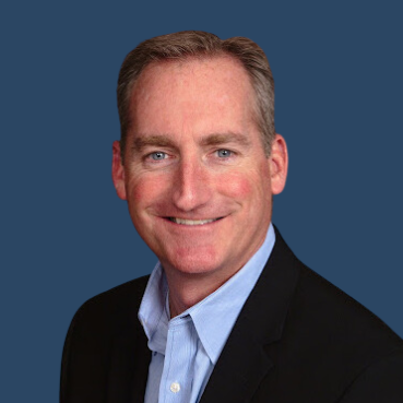A man in a suit and blue shirt smiles for the camera