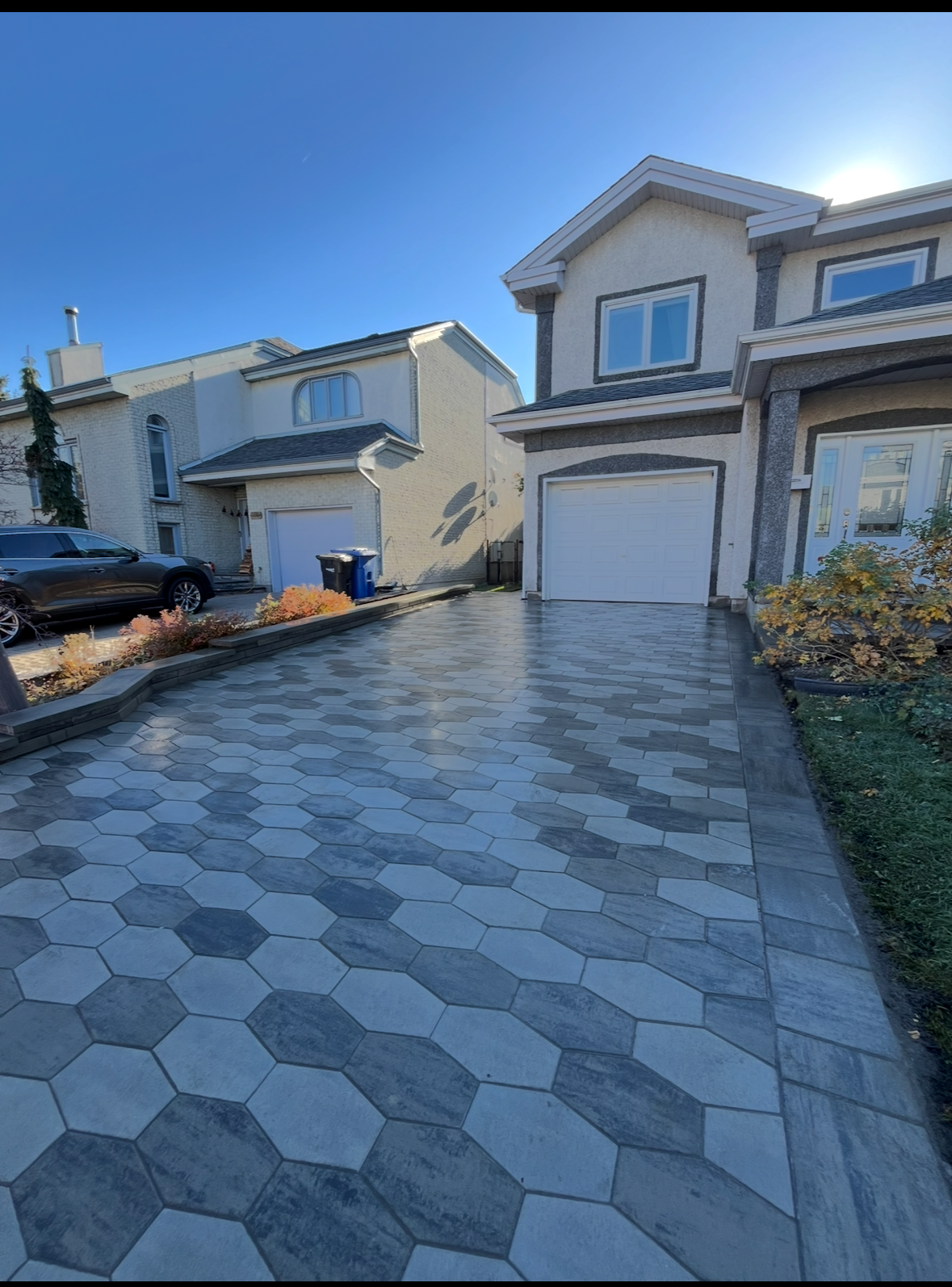 Une allée menant à une maison avec une voiture garée devant.