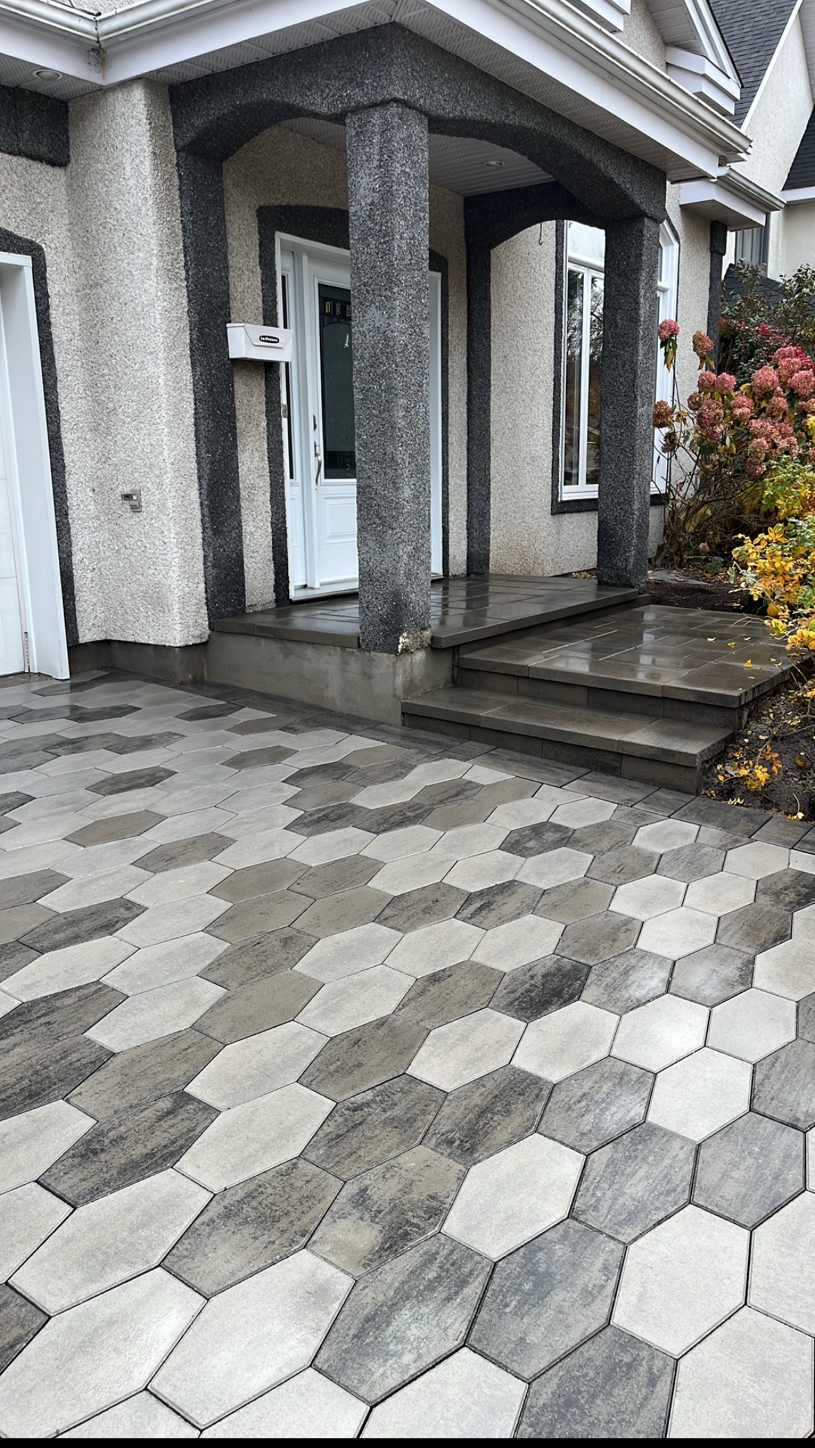 Une maison avec un porche et une allée en briques devant.