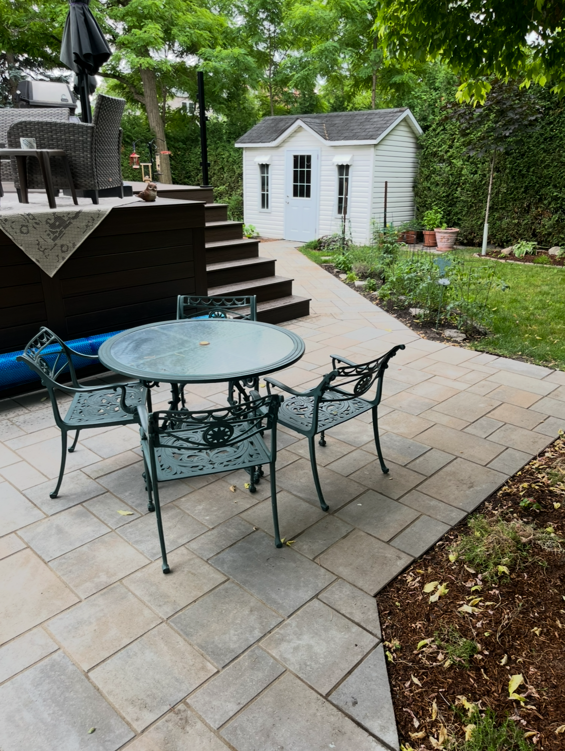 Un patio avec une table et des chaises et un cabanon en arrière-plan.