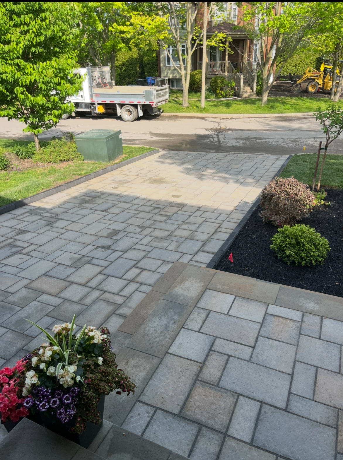 Un patio avec des fleurs et un camion garé en arrière plan.