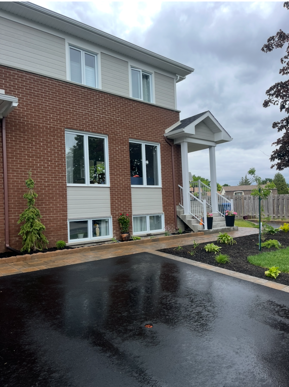 Une maison en briques avec une allée noire devant elle