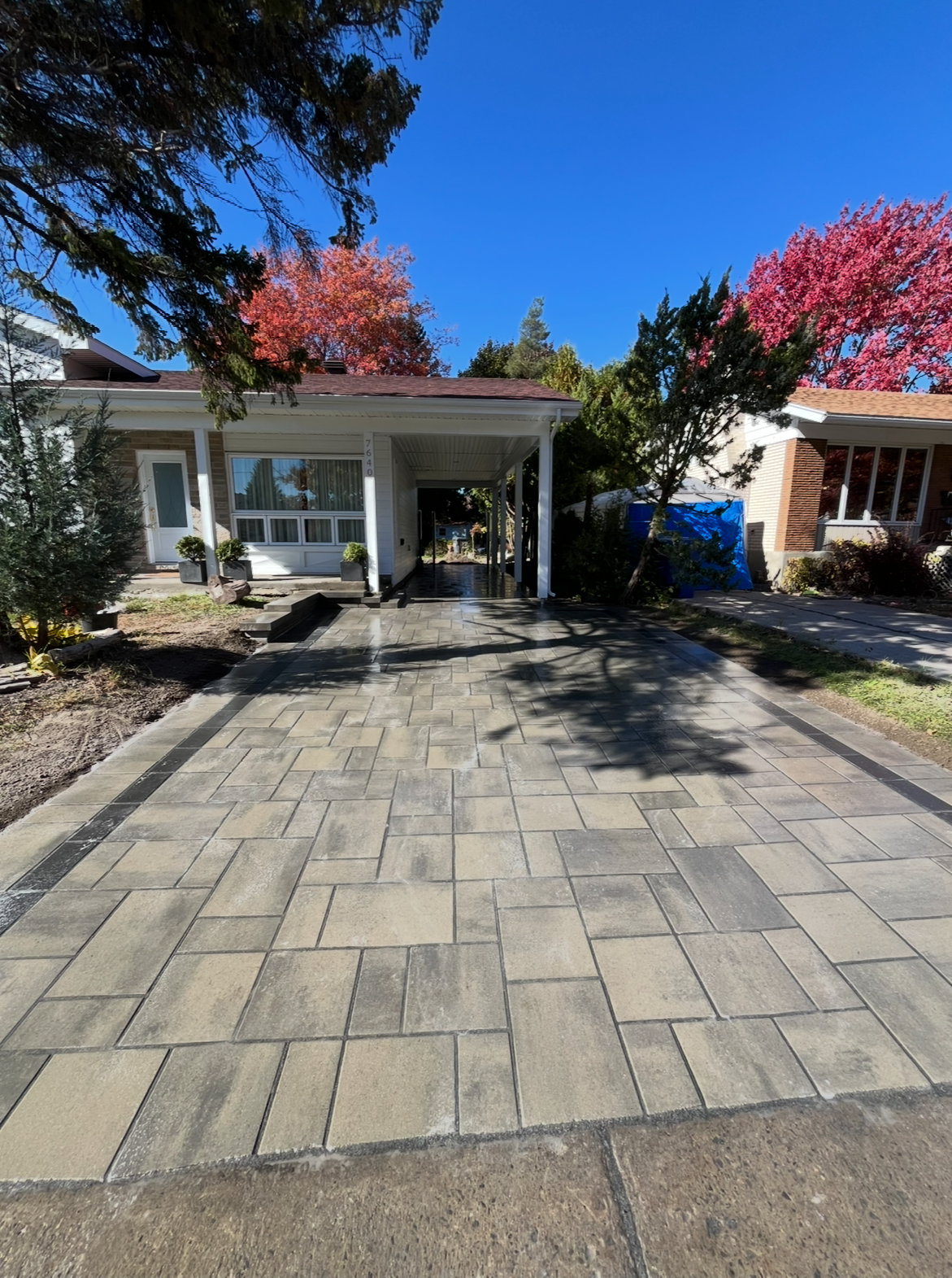 Une allée en briques menant à une maison avec un abri voiture.